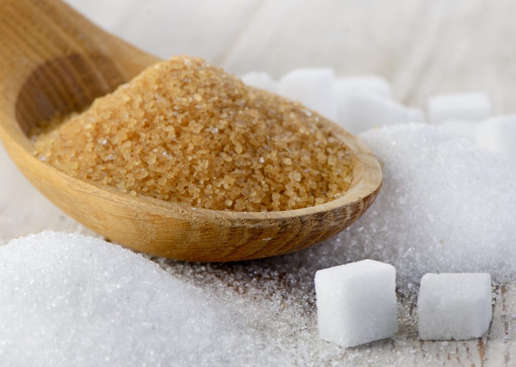 Brown sugar and white sugar cubes in a wooden spoon, symbolizing agricultural trading and quality sugar products