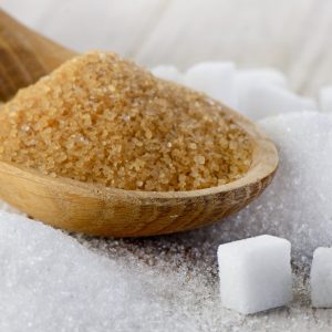 Brown sugar and white sugar cubes in a wooden spoon, symbolizing agricultural trading and quality sugar products