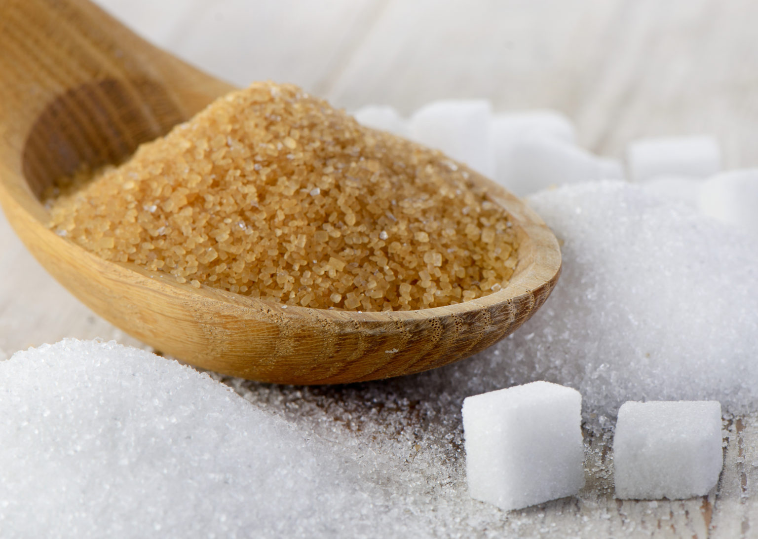 Brown sugar and white sugar cubes in a wooden spoon, symbolizing agricultural trading and quality sugar products
